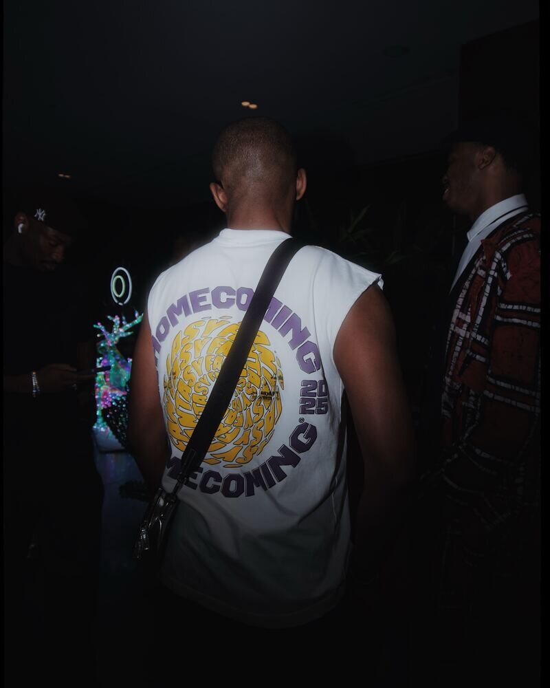 Night crowd, a man in a Homecoming shirt seen from behind