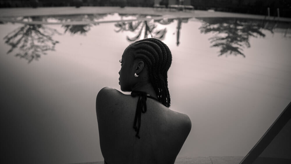 Silhouette of a woman with braids from behind, by water