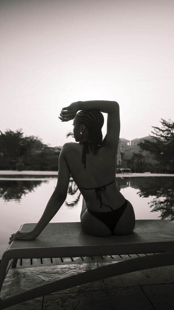 Black-and-white portrait of a woman stretching by a pool
